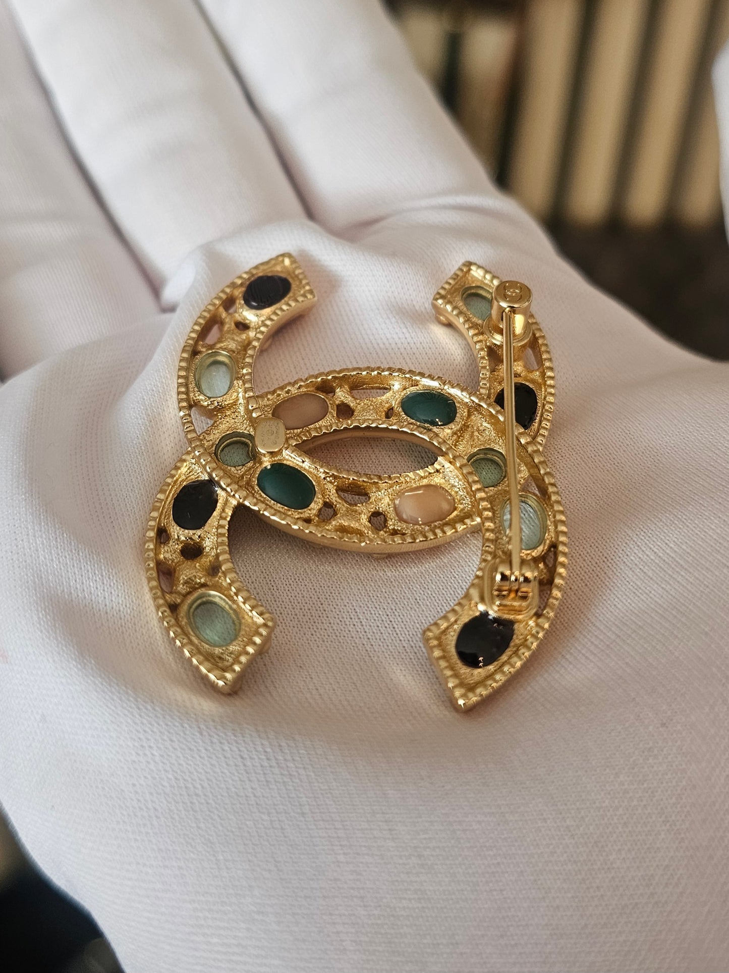 Chanel golden broche with multicolorwd stones.