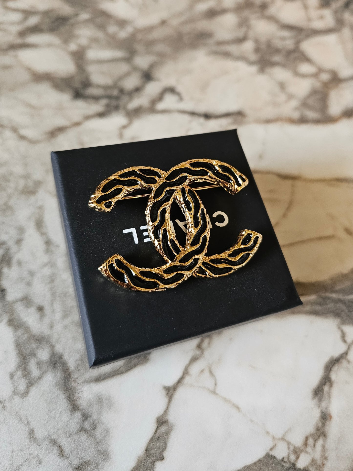 Chanel golden CC broche with black design.