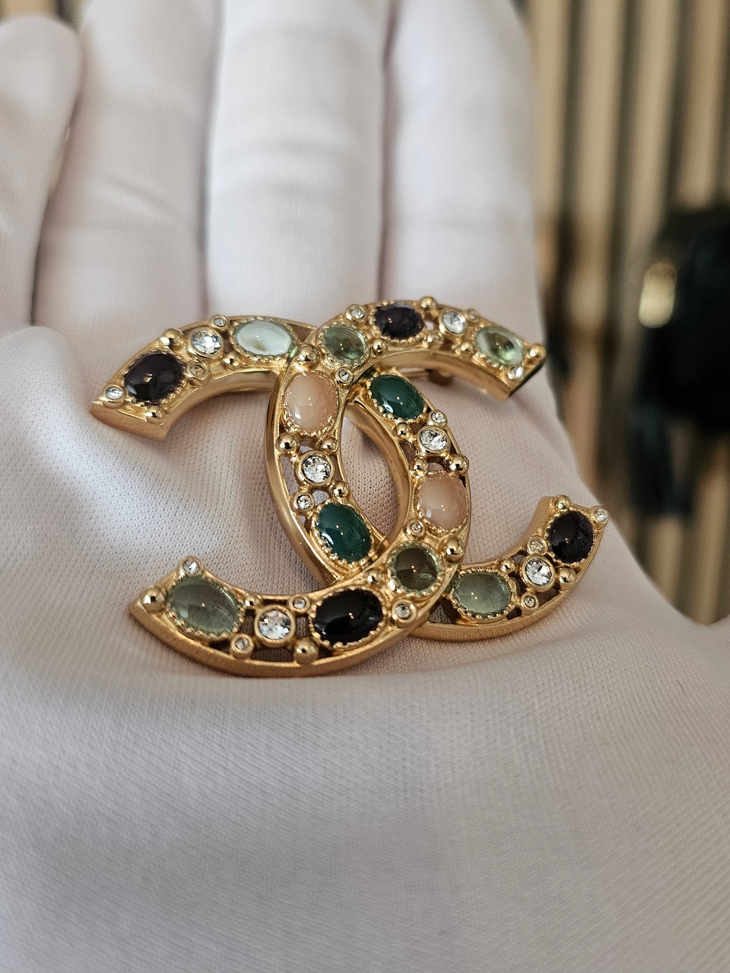 Chanel golden broche with multicolorwd stones.