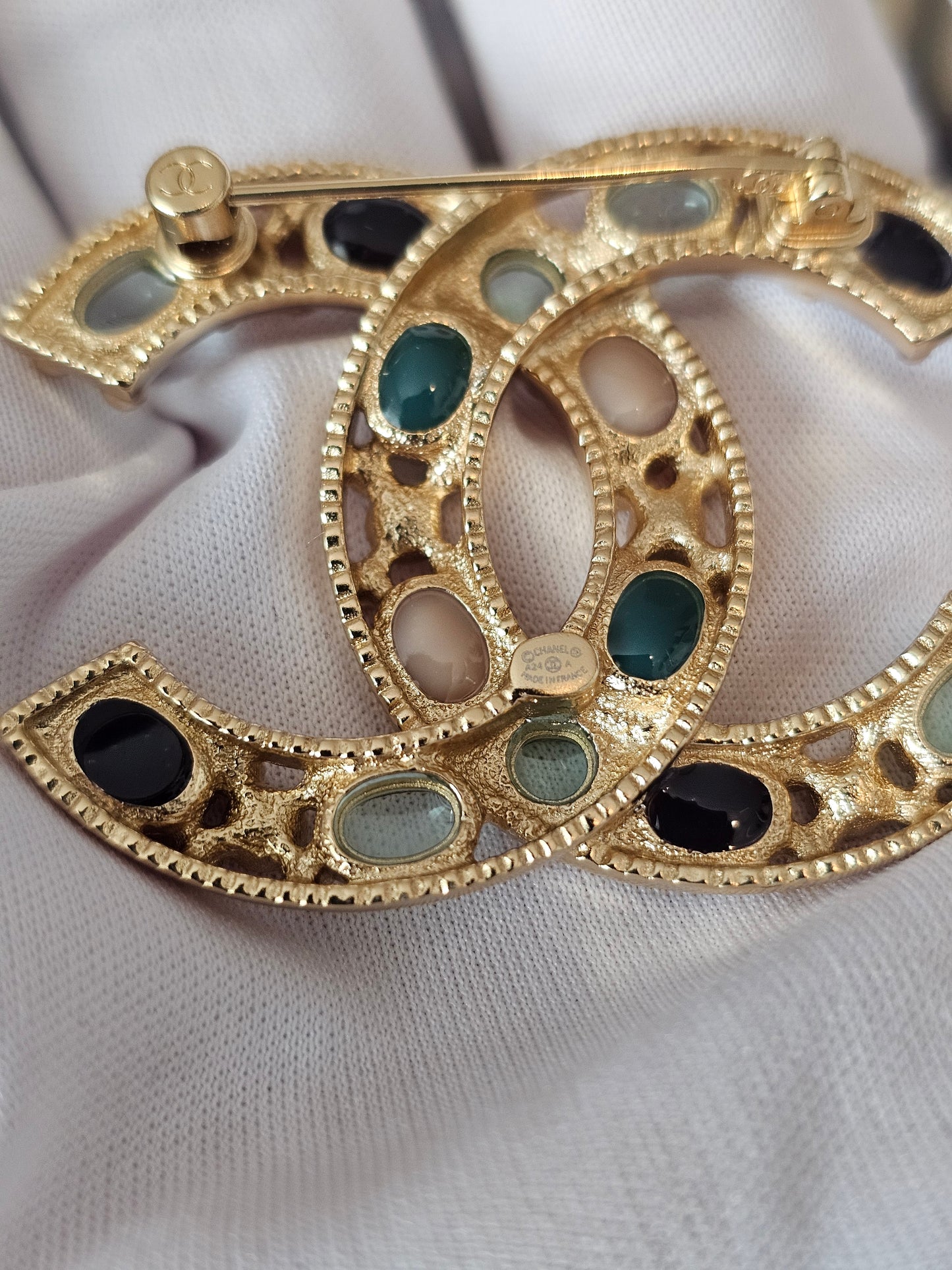 Chanel golden broche with multicolorwd stones.