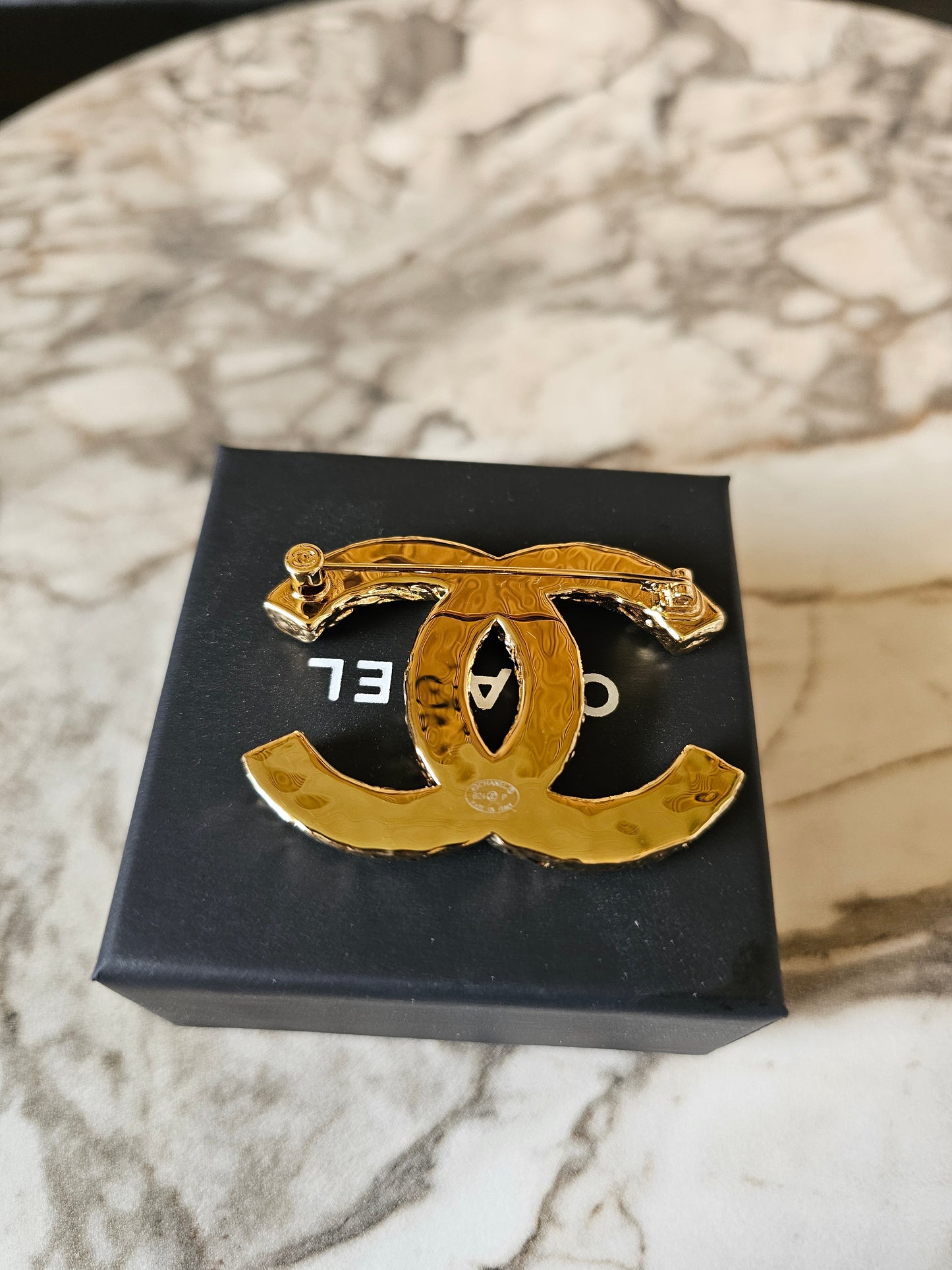Chanel golden CC broche with black design.