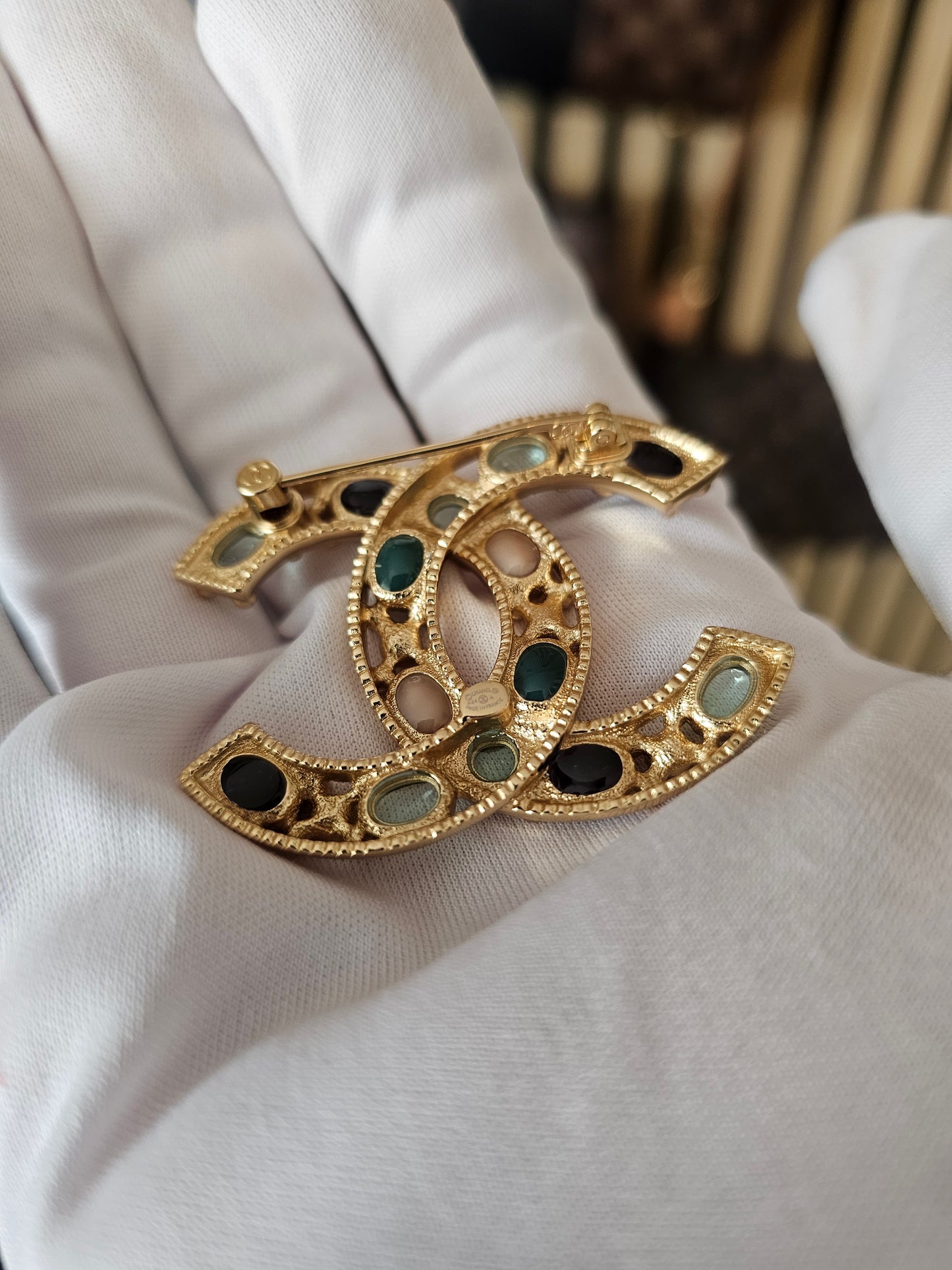Chanel golden broche with multicolorwd stones.