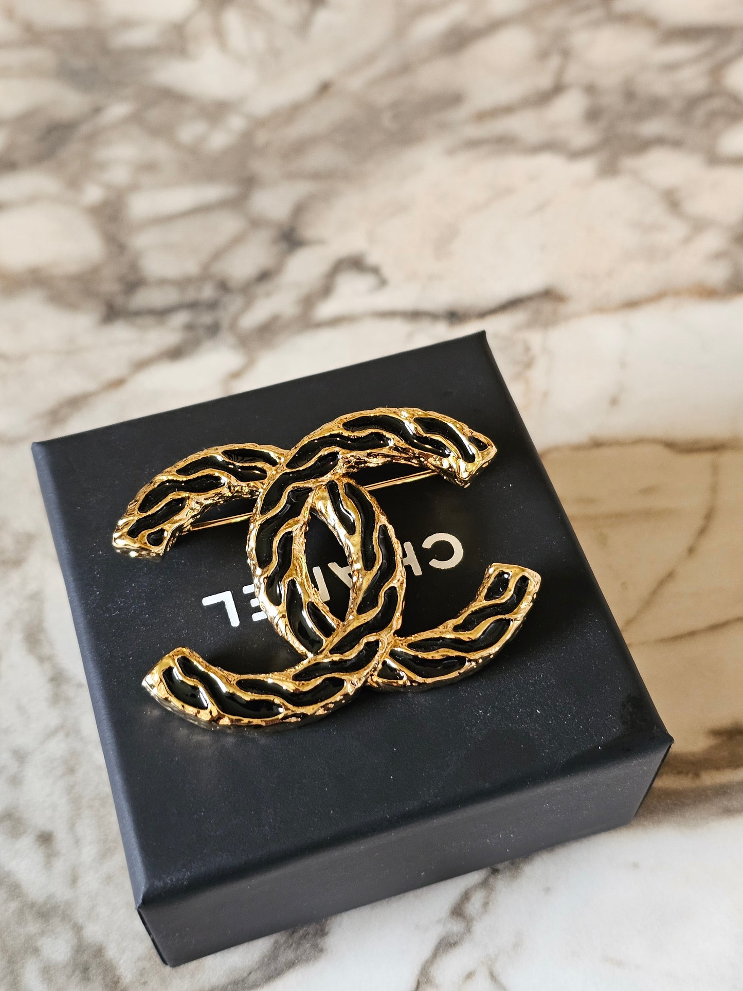 Chanel golden CC broche with black design.