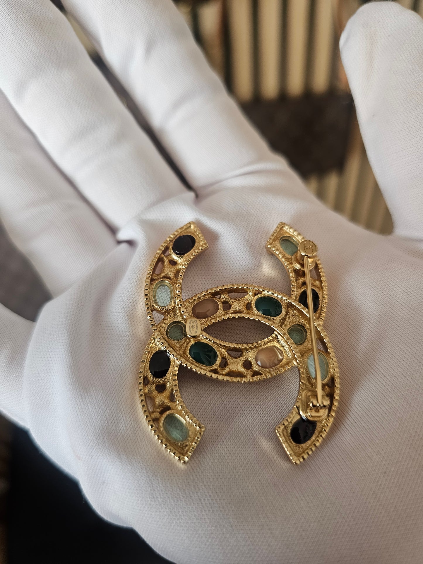 Chanel golden broche with multicolorwd stones.