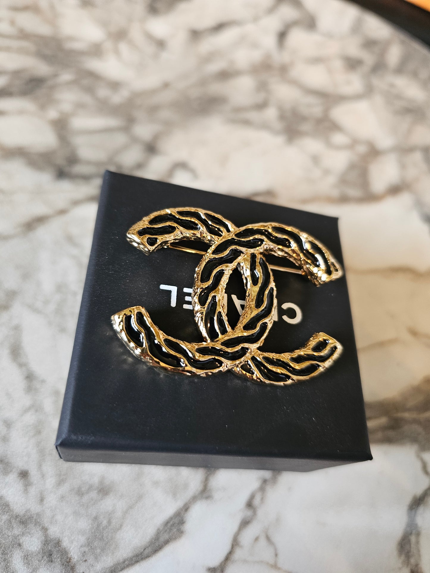 Chanel golden CC broche with black design.