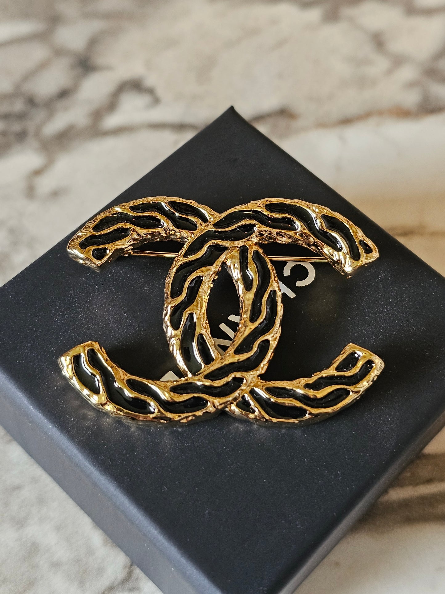 Chanel golden CC broche with black design.